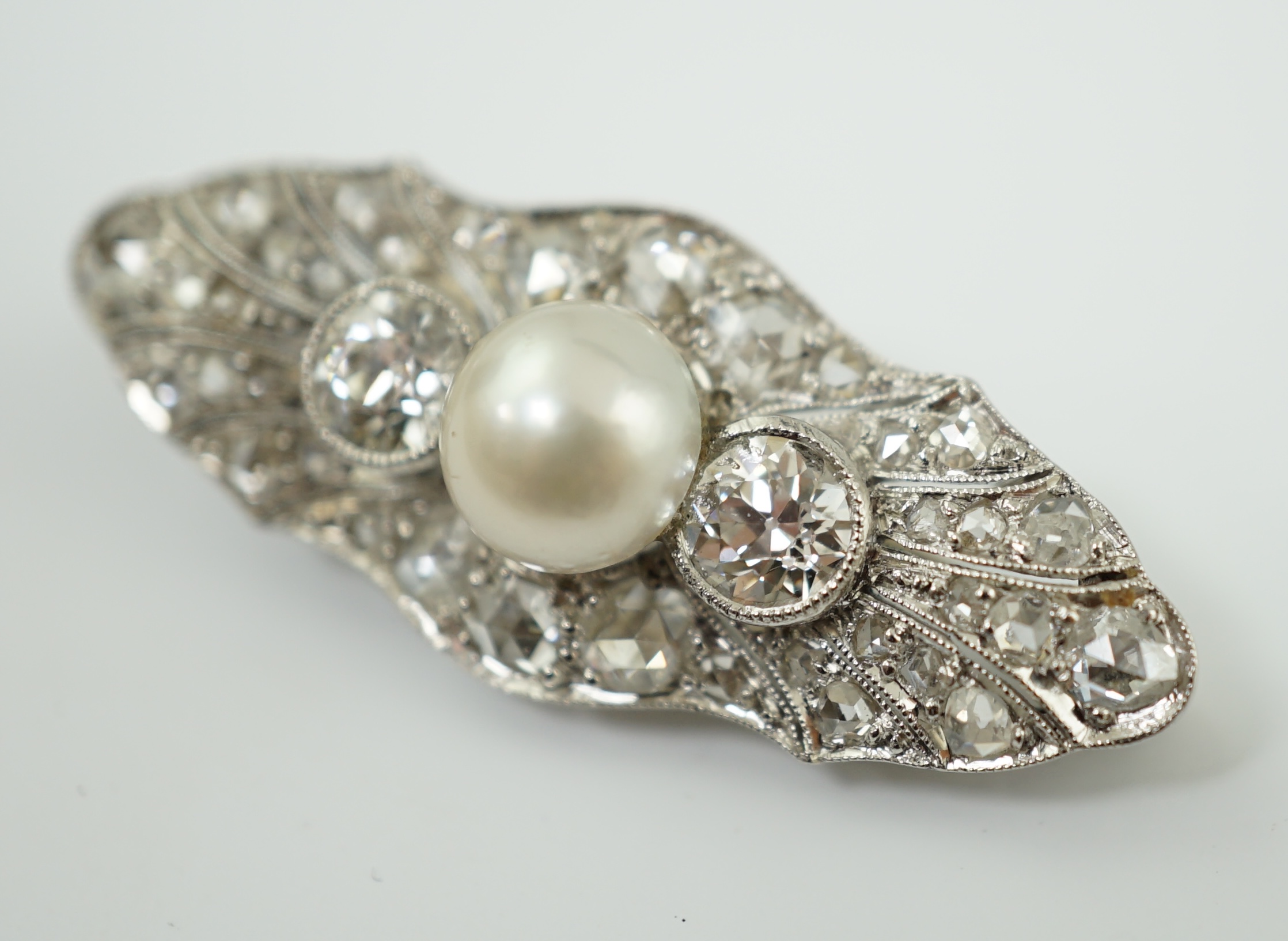 A Belle Epoque white gold, single stone split pearl and millegrain set diamond cluster lozenge shaped brooch